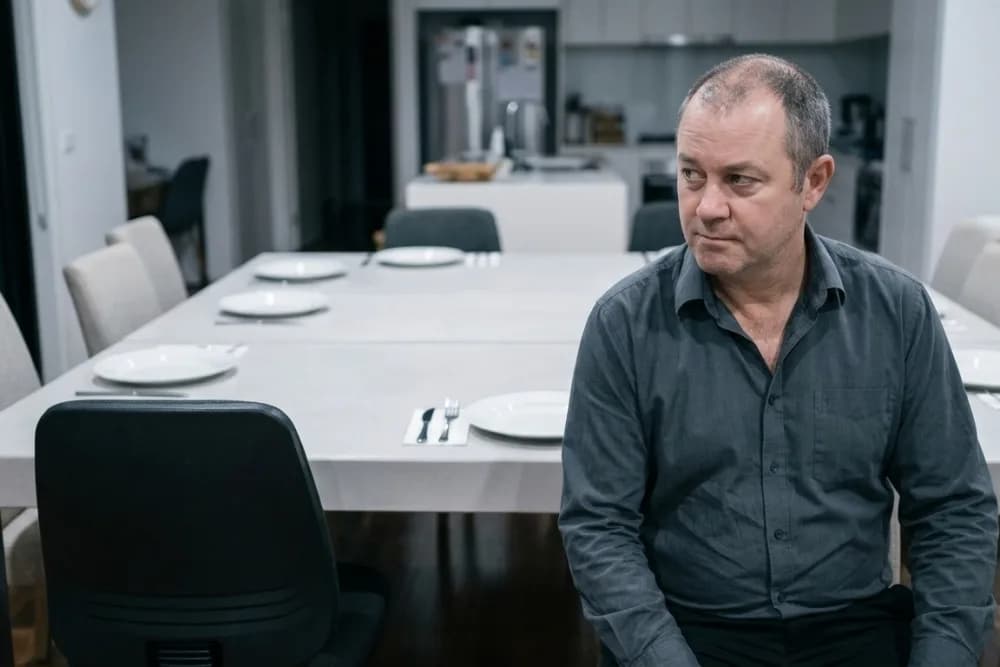 A long dining table set for a meal with one end of the seating unoccupied.